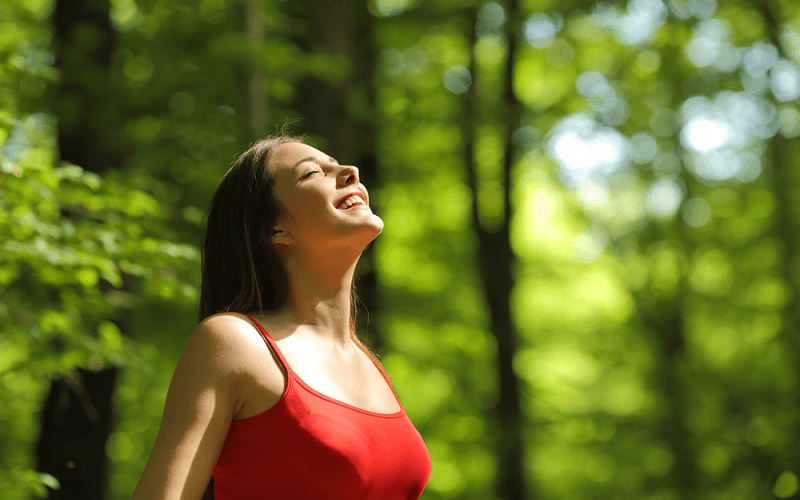 森林で深呼吸する笑顔の女性画像